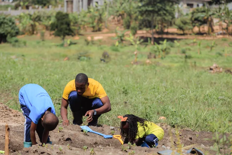 An educator and young learners exploring the school garden