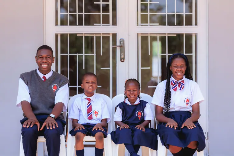 Learners sitting together outside a school building