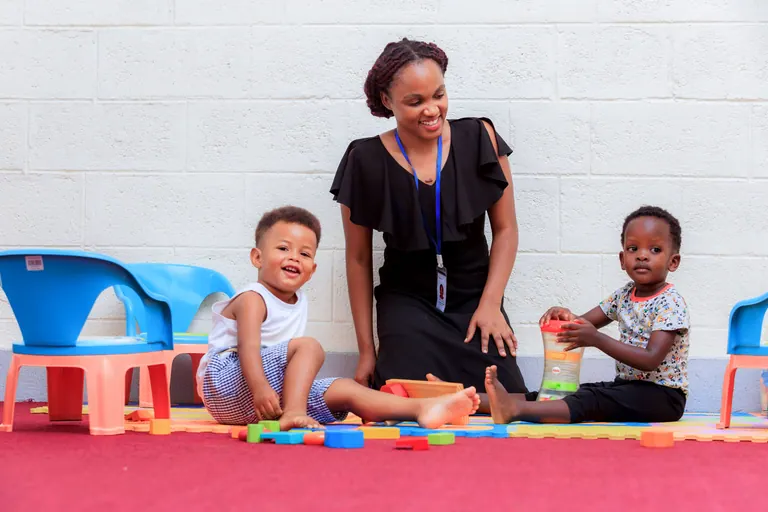 An educator and young children playing with classroom toys