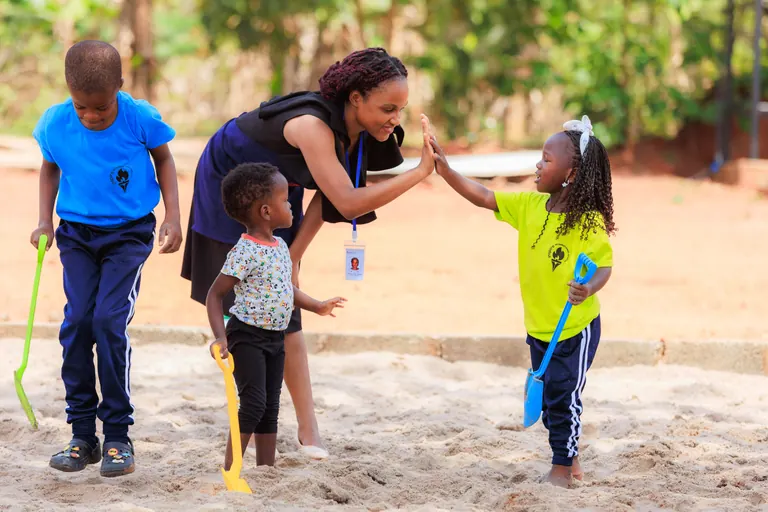 An educator guiding young learners in outdoor play