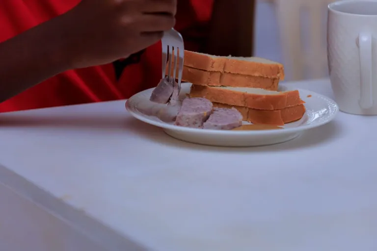 A plate of bread and sliced food with a cup