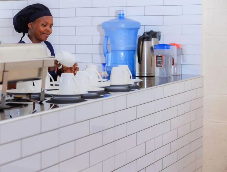 A staff member pouring a drink at a serving counter