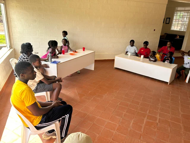 Adults and children seated around tables during an indoor group discussion