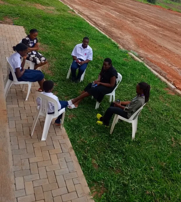 Six people seated in a small discussion circle outdoors